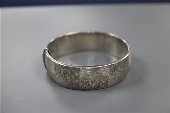 A 1970s textured silver hinged bracelet, with checkered decoration, by Rigby & Wilson, gross 46 grams.